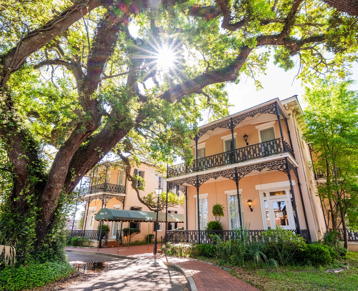 Malaga Inn in downtown Mobile with sunlight shining through trees