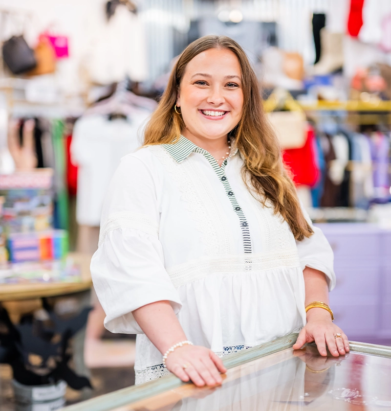 Headshot photo of Nikki Moore director of Urban Emporium, standing at jewelry display smiling